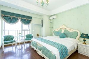 a bedroom with a blue and white bed and two chairs at Dalian Hong Xi Yuan Apartment Wanda Plaza in Dalian