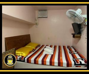 a small bedroom with a bed and a fan at White Knights Dumaguete in Dumaguete