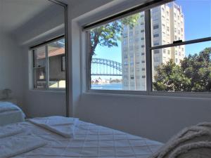 Schlafzimmer mit einem Bett und einem Fenster mit Blick auf eine Brücke in der Unterkunft Spectacular Views of Sydney Harbour with Free Parking in Sydney