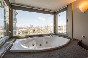 a large bath tub in a room with a large window at Taxim Suites Residences Istanbul in Istanbul