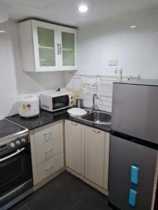 a small kitchen with a refrigerator and a sink at Omni Tower 2 Bed Room Sukhumbit Best Apartment in Bang Kapi