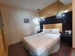 1 dormitorio con 1 cama blanca grande y cabecero negro en 2 Inn 1 Boutique Hotel & Spa, en Sandakan