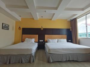 two beds in a hotel room with two beds at 2 Inn 1 Boutique Hotel & Spa in Sandakan