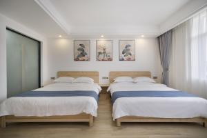 2 camas en una habitación con paredes blancas en Qianxun Tea House & Homestay, en Wuyishan