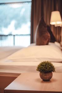 a potted plant sitting on top of a bed at Hotel Plan De Gralba - Feel the Dolomites in Selva di Val Gardena