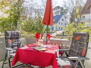 uma mesa com uma toalha de mesa vermelha e duas cadeiras em Villa A Cappella - WG 1 "Gelbe Orchidee" em Binz