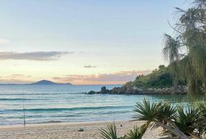 a beach with a view of the ocean with palm trees at Haliaeetus@Hat in Hat Head