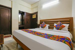a bedroom with a large bed with a colorful blanket at FabHotel Ashoka Inn in Kānpur