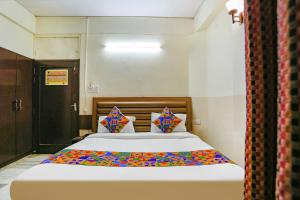 ein Schlafzimmer mit einem großen Bett mit bunter Bettwäsche und Kissen in der Unterkunft FabHotel Ashoka Inn in Kānpur