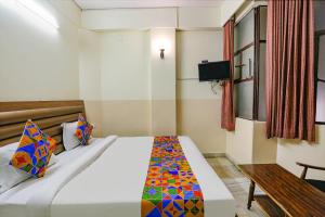 a bedroom with a bed and a table and a television at FabHotel Ashoka Inn in Kānpur