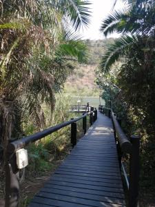 a wooden pathway with palm trees and a person walking down it at Eden Wilds Unit 125 in Port Edward