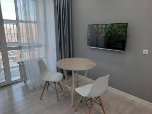 ein Esszimmer mit einem Tisch und Stühlen sowie einem TV in der Unterkunft Апартаменты на Кенесары 83 in Kökschetau