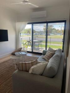 a living room with a couch and a view of a patio at Quarterdeck Lakes Entrance 2br *Waterfront* Apartment in Lakes Entrance