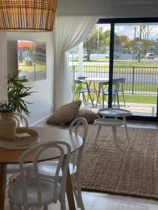 a living room with a table and chairs and a patio at Quarterdeck Lakes Entrance 2br *Waterfront* Apartment in Lakes Entrance
