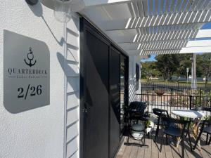a patio with tables and chairs and a sign on a building at Quarterdeck Lakes Entrance 2br *Waterfront* Apartment in Lakes Entrance