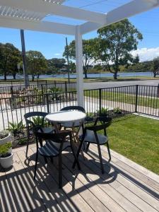 um pátio com uma mesa e cadeiras num deque em Quarterdeck Lakes Entrance 2br *Waterfront* Apartment em Lakes Entrance