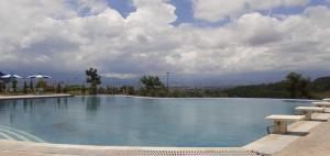 een groot zwembad met banken en een bewolkte hemel bij The Valley Guesthouse in Malang