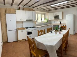 una cucina con tavolo, sedie ed elettrodomestici bianchi di Casa Rural "La villa del pistacho" ad Archivel