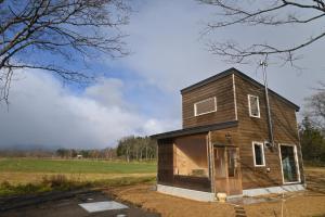 a tiny house on the side of a field at 小さな森の貸し切り宿Forest-House-Ranapirica in Shibetsu