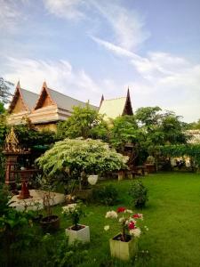 une maison avec des arbres et des plantes dans une cour dans l'établissement MrT Riverside Sampran มิสเตอร์ที โฮมสเตย์-ทองกวาว, à Sam Phran