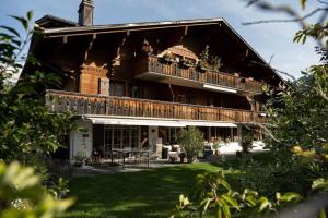 Charming Alpine Apartment Gstaad في غشتاد: منزل كبير مع شرفة وطاولة