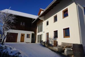 a large white building with snow on the ground at Ferienwohnung Haus Brenner in Seeg