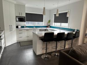 a kitchen with white cabinets and a island with bar stools at Home Away from Home in Napier