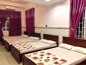 um quarto com três camas e cortinas roxas em 2001 Motel em Long Hai