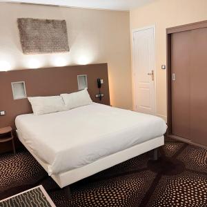 a bedroom with a large white bed in it at Le Grand Hotel in Valenciennes