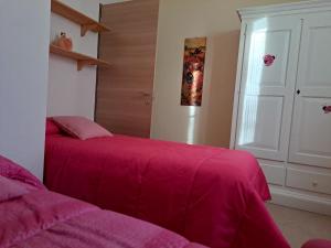 Schlafzimmer mit einem Bett mit rosa Bettwäsche und einer Tür in der Unterkunft HomeRaffa in Ovodda