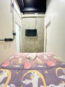 a bedroom with a bed with a purple comforter at Sleepbox Hostel Suratthani in Surat Thani