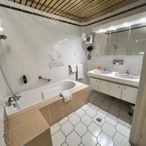 a bathroom with two sinks and a tub and a mirror at Le Grand Hotel in Valenciennes