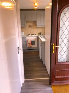 a kitchen with white cabinets and an open door at Tovey Lodge in Hassocks