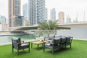 a patio with two chairs and a table on the grass at Boutique Living - Marina Wharf in Dubai