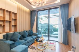 a living room with a blue couch and a large window at Sunny Vinhome Metropolis Apartment in Hanoi