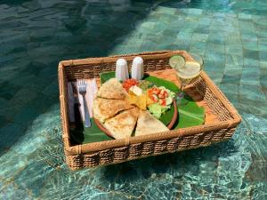 a wicker basket with a plate of food on it at Katara Gili, Boutique Rooms and Bungalows in Gili Trawangan
