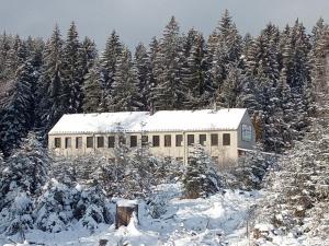 a building covered in snow in front of trees at Penzion Šumavous in Vimperk