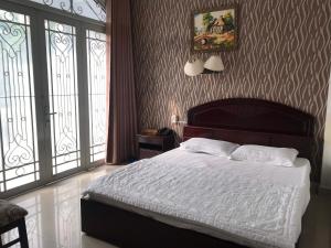 een slaapkamer met een bed met witte lakens en 2 ramen bij khách sạn Hồng Tâm in Ho Chi Minh-stad