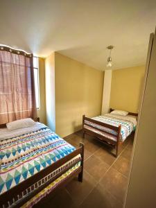 een slaapkamer met 2 bedden en een raam bij Cálido Departamento en Chincha Alta in Chincha Alta
