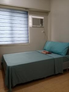 a bedroom with a bed and a window with a fan at Sunvida Cebu in Cebu City