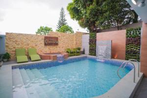 a swimming pool with green chairs and a table at Balay Greenika Tagaytay Private Pool in Tagaytay
