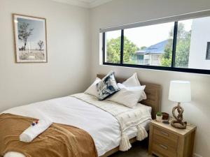 a white bedroom with a bed with a window at Luxurious 2-Bed with Alfresco Balcony & Parking in Brisbane