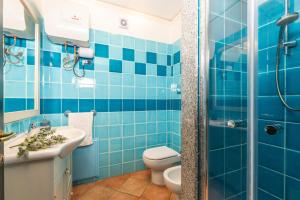 a blue tiled bathroom with a toilet and a sink at Casa il grande Carrubo in Santa Maria Navarrese +40 photos