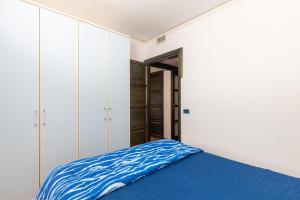 a bedroom with white cabinets and a blue bed at Casa il grande Carrubo in Santa Maria Navarrese