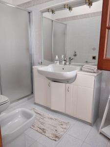 a white bathroom with a sink and a toilet at Appartamento Marco a pochi passi dal mare S.Vito in San Vito lo Capo