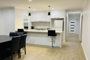 a kitchen with white cabinets and a table and chairs at Rose Villa Bendigo in Kennington