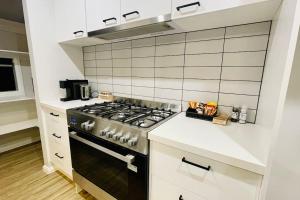 Rose Villa Bendigo في Kennington: مطبخ مع موقد ودواليب بيضاء