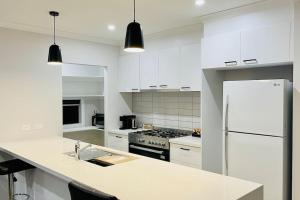 a white kitchen with a sink and a refrigerator at Rose Villa Bendigo in Kennington