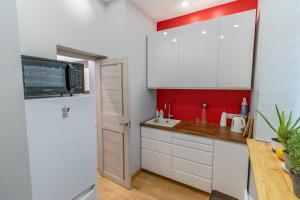 a kitchen with white cabinets and a red accent wall at Apartment Windau in Ventspils +4 photos