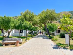 a sidewalk with benches and trees in a park at VOI Le Muse Essentia in Zambrone